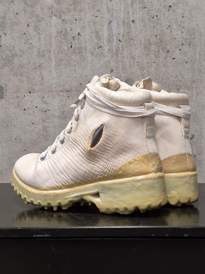 White boot with beige sole on a concrete surface