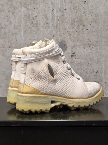 Pair of white and beige boots on a concrete surface