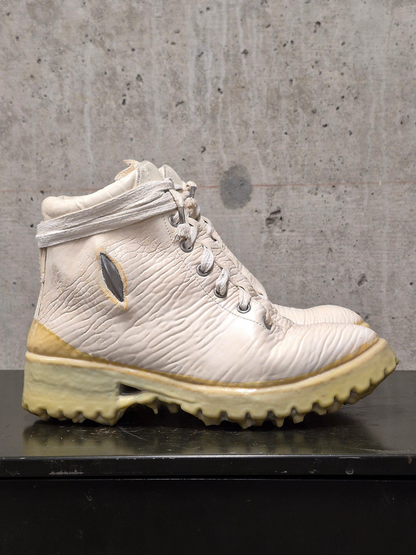 White hiking boot with yellow sole on a concrete surface