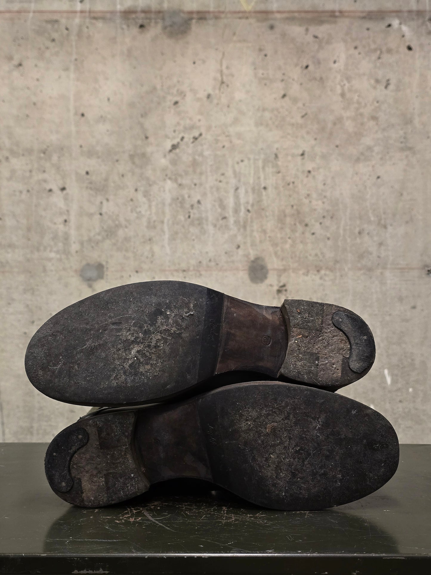 Pair of worn black shoes on a concrete floor