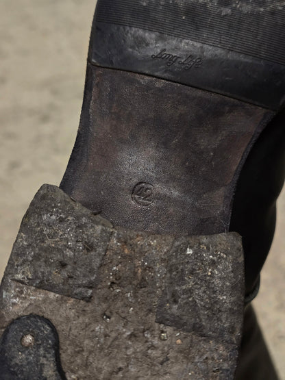 Close-up of a worn boot sole with a brand logo on a sandy background