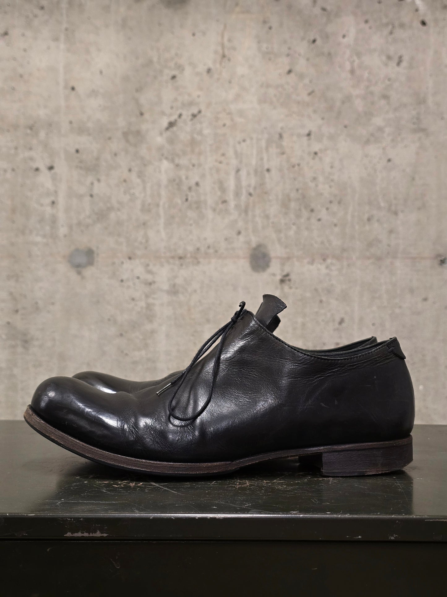 Black leather shoe on a concrete surface