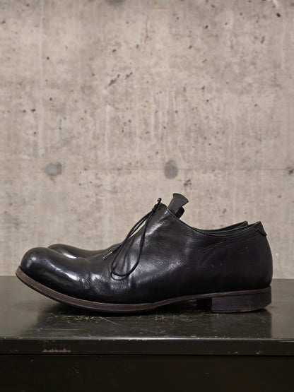 Black leather shoe on a concrete surface