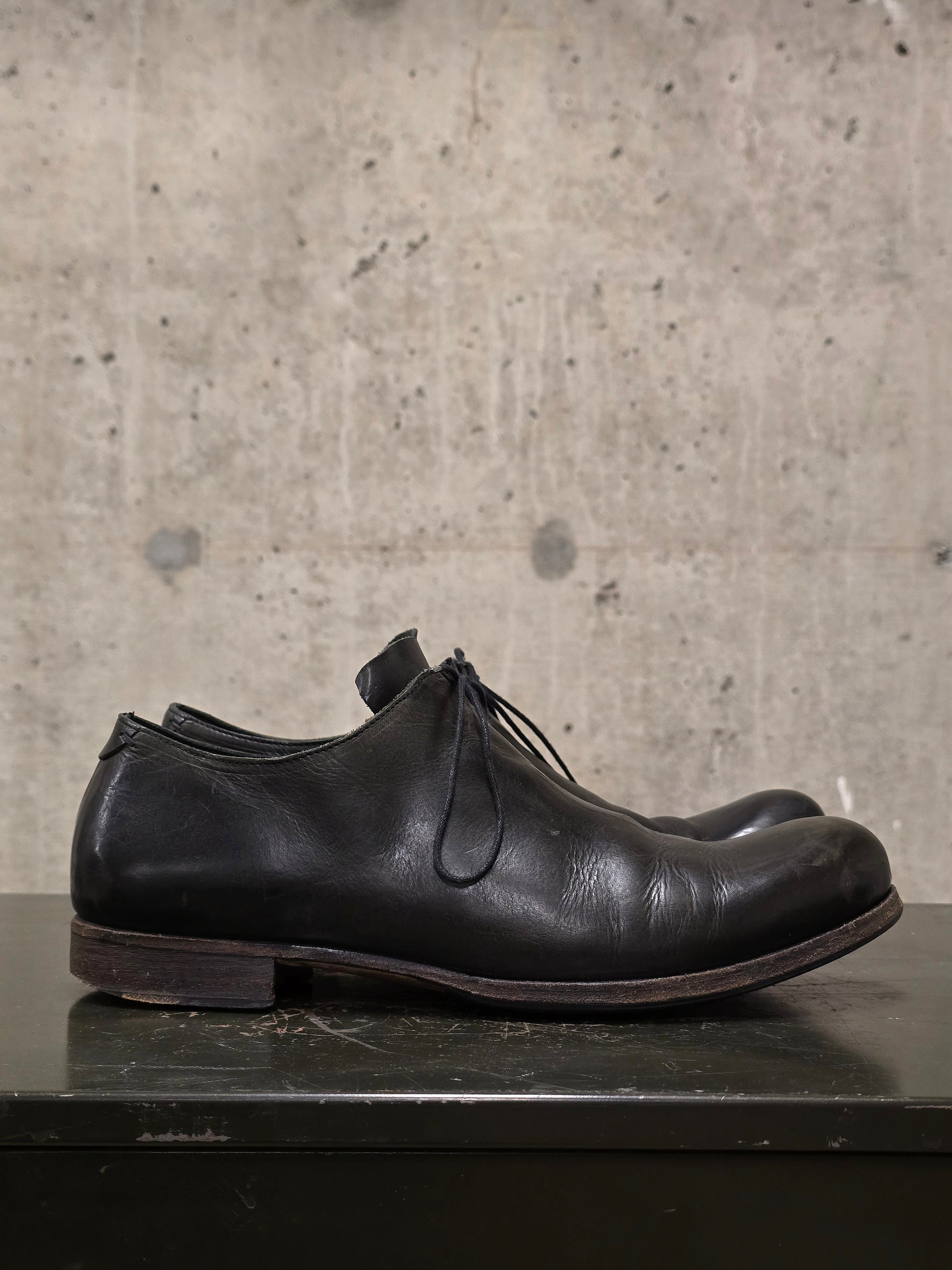 Black leather shoe on a concrete surface
