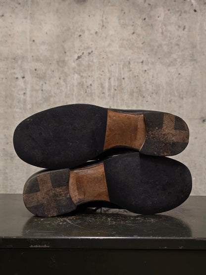 Pair of worn shoes with brown soles on a concrete surface