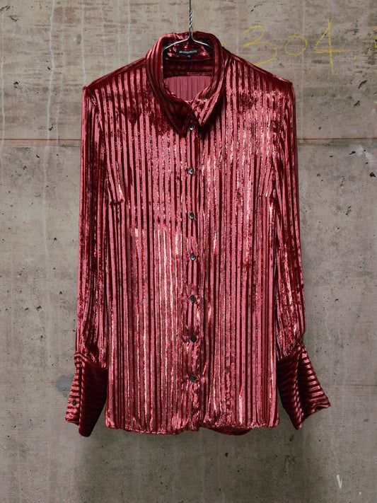 Red velvet shirt on a hanger against a textured gray wall.