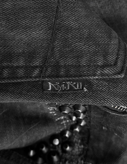 A close-up of KMRii Early 00s Goatskin Patches Studded Crush Flare-zip Denim in Size 2 shows black denim with a small black NMRIK label, subtle fading, and black beads partially visible below the fabric.