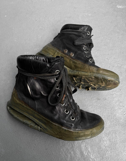 A pair of DRIEW Carol Christian Poell ‘AM/2685P ROOMS-PTC/12’ black high-top kangaroo leather sneakers (Size 6, EU 41.5-42) with thick translucent green soles, light wear, scuffs, creases, and loosely tied black laces rest on a gray surface.
