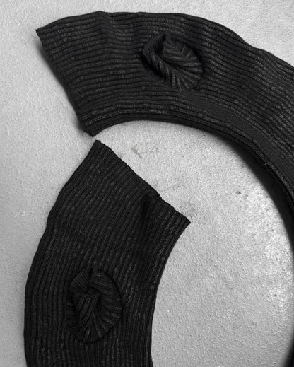 Two black, curved wax coated gloves from DRIEW’s Julius_7 AW24-25 “rift;” line are displayed on a light surface. Their flawless one-size design and textured finish stand out in this black-and-white shot.