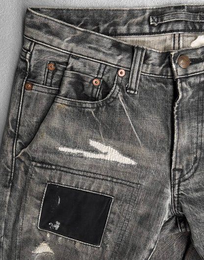 A close-up of Mihara Yasuhiro AW10 Double-pockets Repair Patchwork Selvedge Denim shows distressed gray jeans with fading, rips, frayed edges, copper rivets, and a dark repair patch—reflecting Mihara Yasuhiros signature streetwear edge.