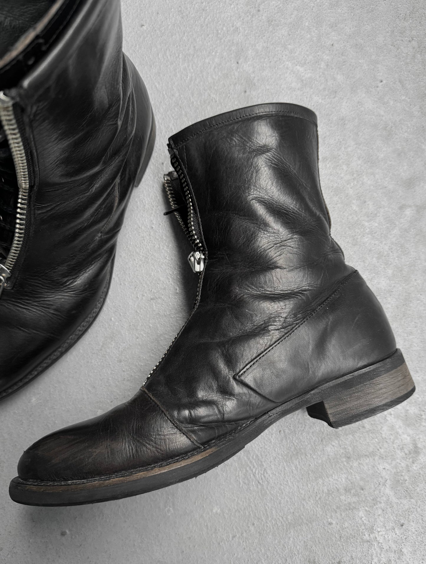 Black leather boots with zippers on a gray surface