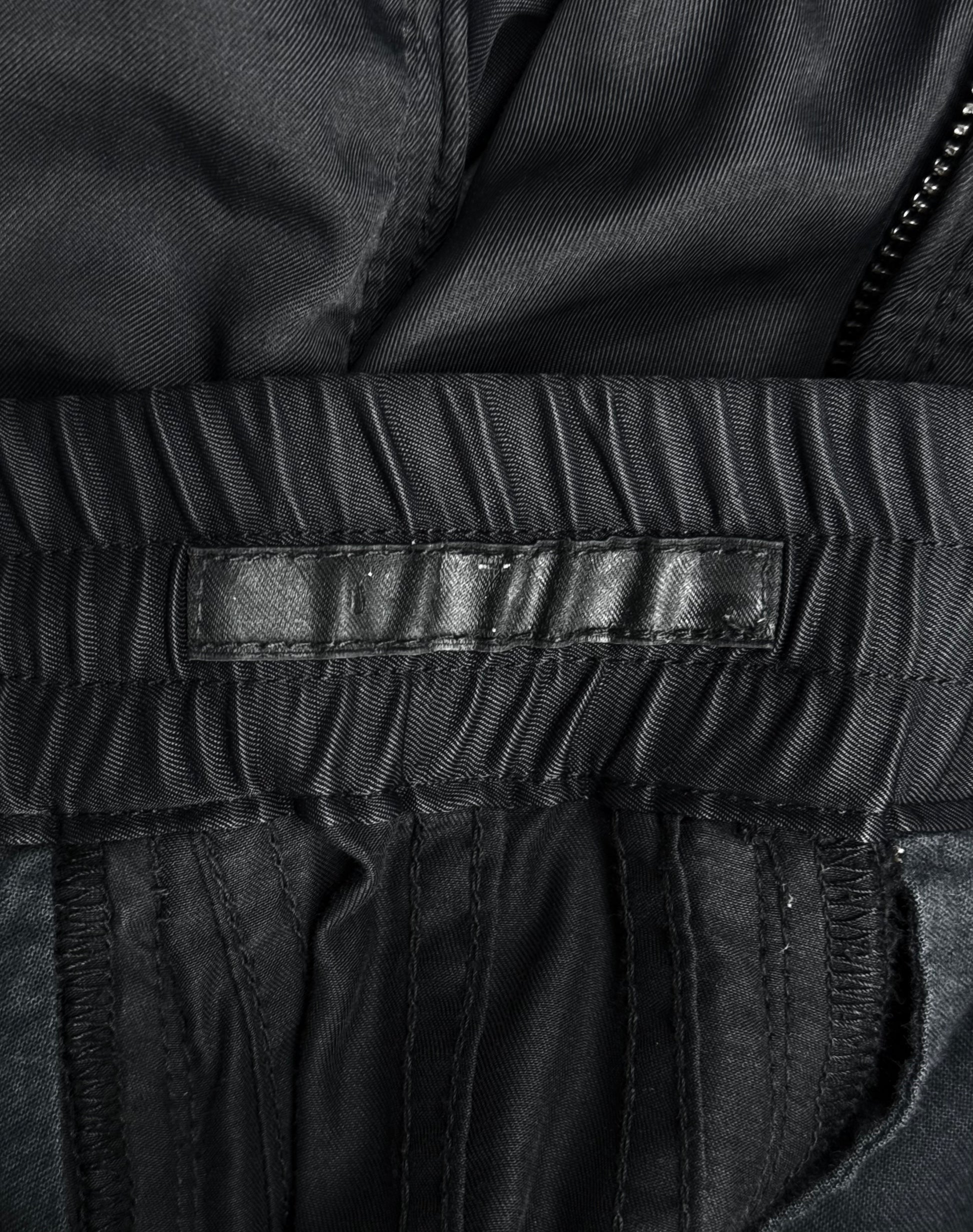Close-up of the inside waistband of Julius_7 SS10 “neurbanvolker;” Convertible Multi-zip Cotton Twill Shorts by DRIEW in black, showing an empty black leather label, gathered fabric, visible stitching, part of a zipper, fits US 29-32 or size 2.