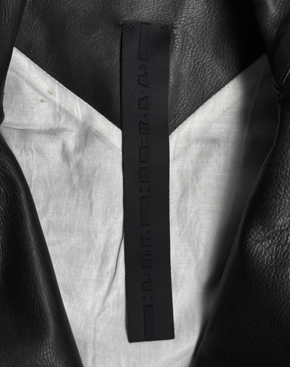 Close-up of the inside collar of a Gareth Pugh AW09 Detachable Sleeves Horse Leather Rider’s Jacket, showing a black tag with embossed, unreadable characters and a light gray inner lining.