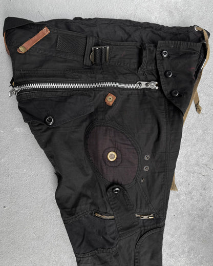 L.G.B Early 00s Pilot Cargo Capris by L.G.B, US 32 Waist, black with multiple zippers, buttons, repair patches, and pockets. Features an asymmetrical design and varied fabric textures. Minor staining visible. Laid flat on a gray surface.