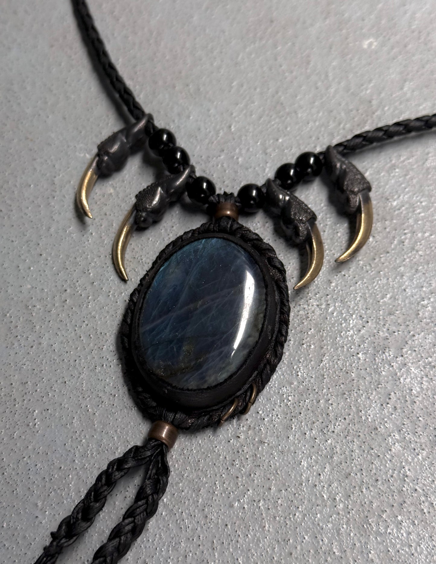 Necklace with black stone pendant and gold accents on a gray background