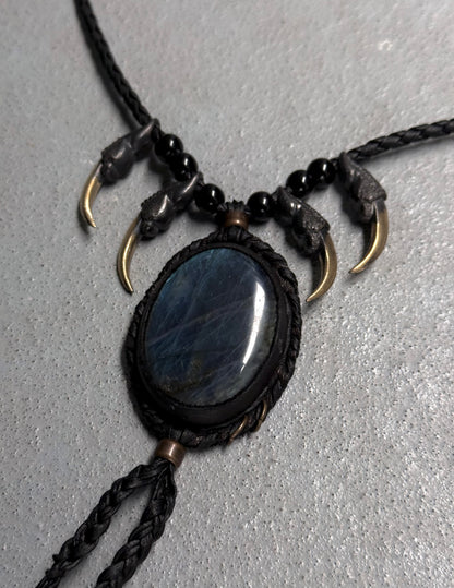 Necklace with black stone pendant and gold accents on a gray background