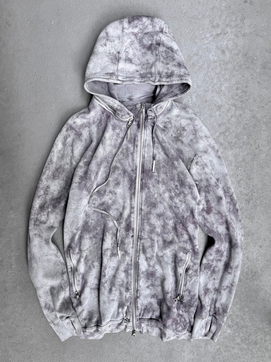 The 11 by Boris Bidjan Saberi SS23 ‘Z1-F1235’ Hand-dyed Convertible Hoodie features a light gray zip-up design with dark gray and purple tie-dye, hood, drawstrings, and front zip pockets—signature avant-garde style from Boris Bidjan Saberi.