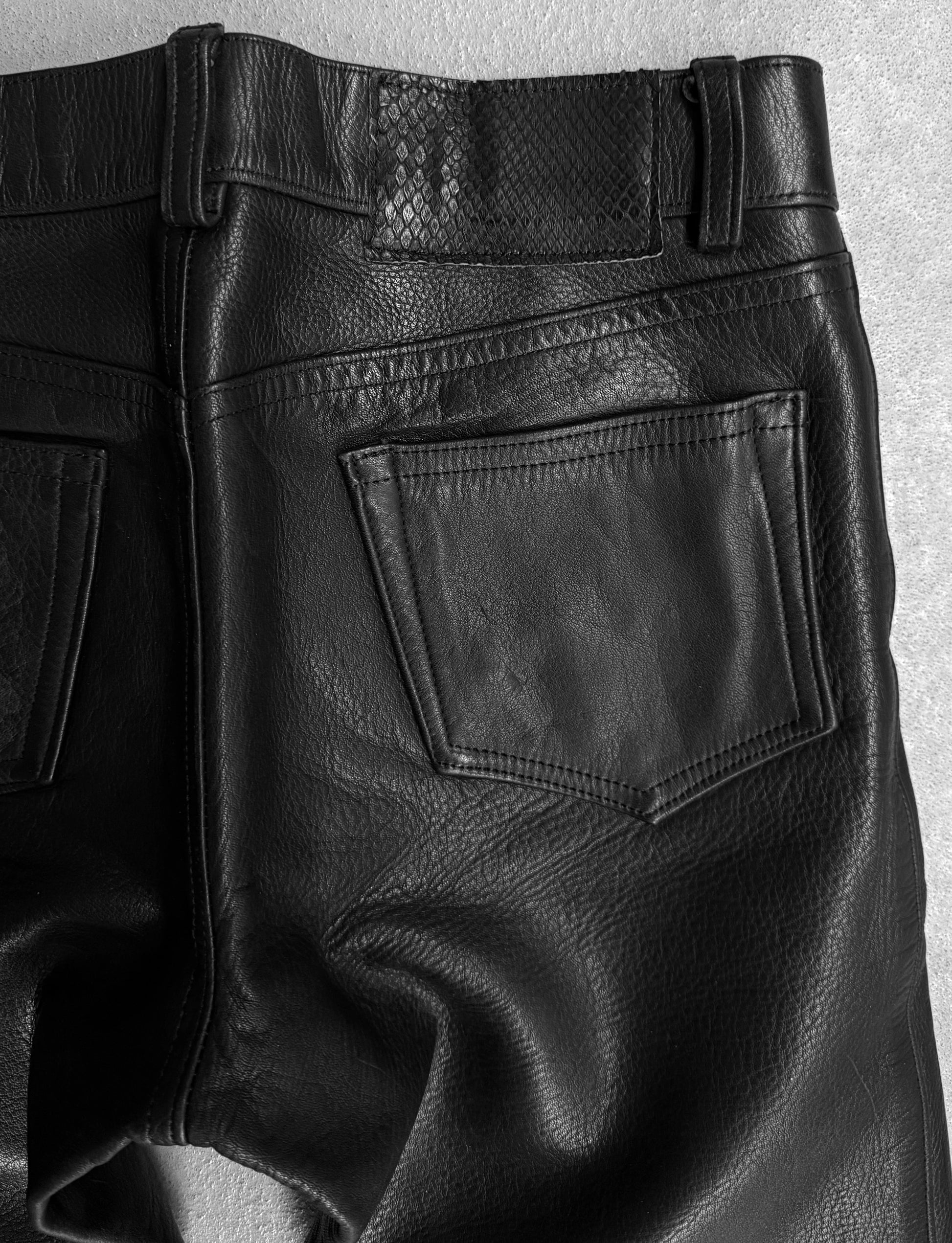 Close-up of black leather pants on a light gray background