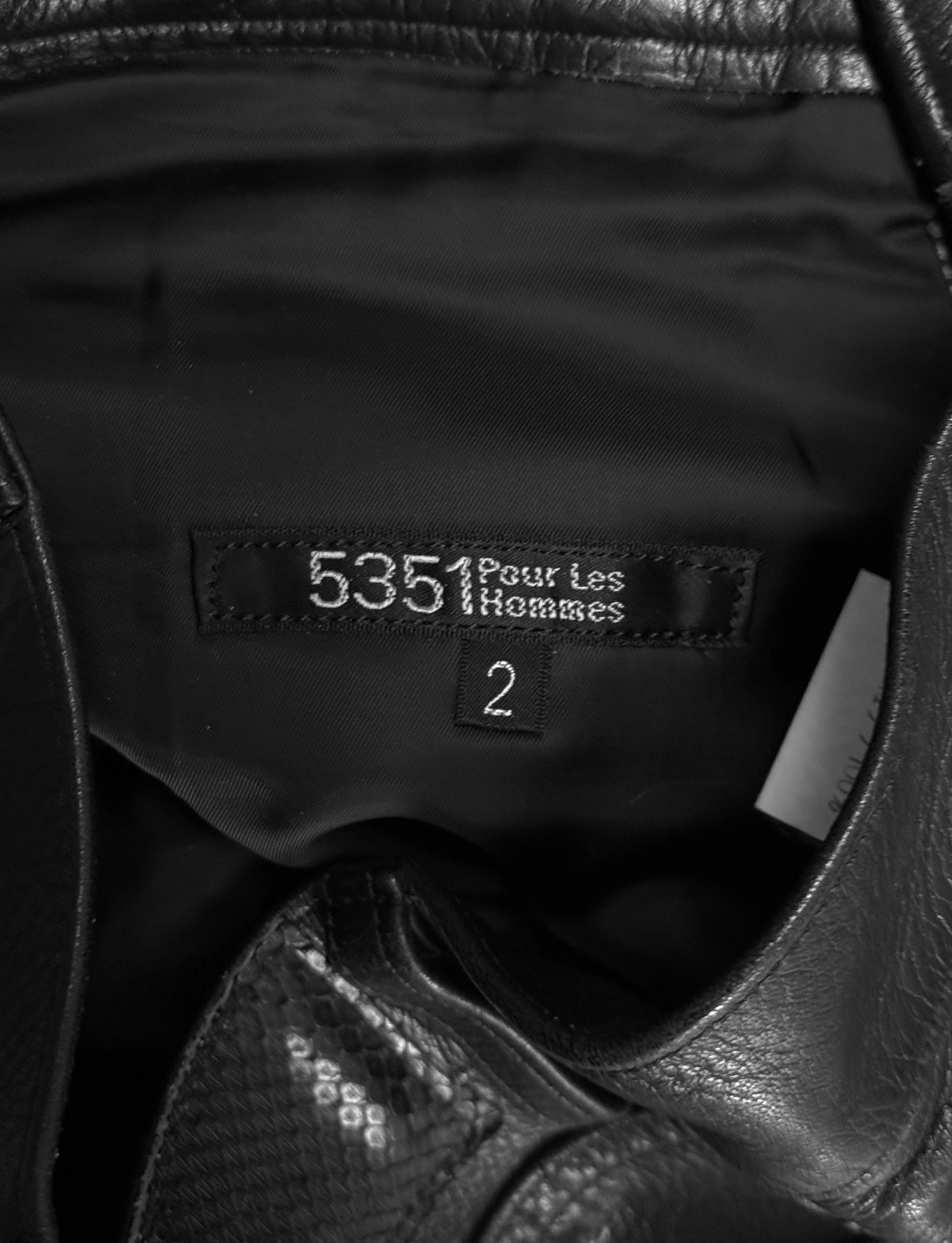 Close-up of a black leather jacket with a brand label on a dark background