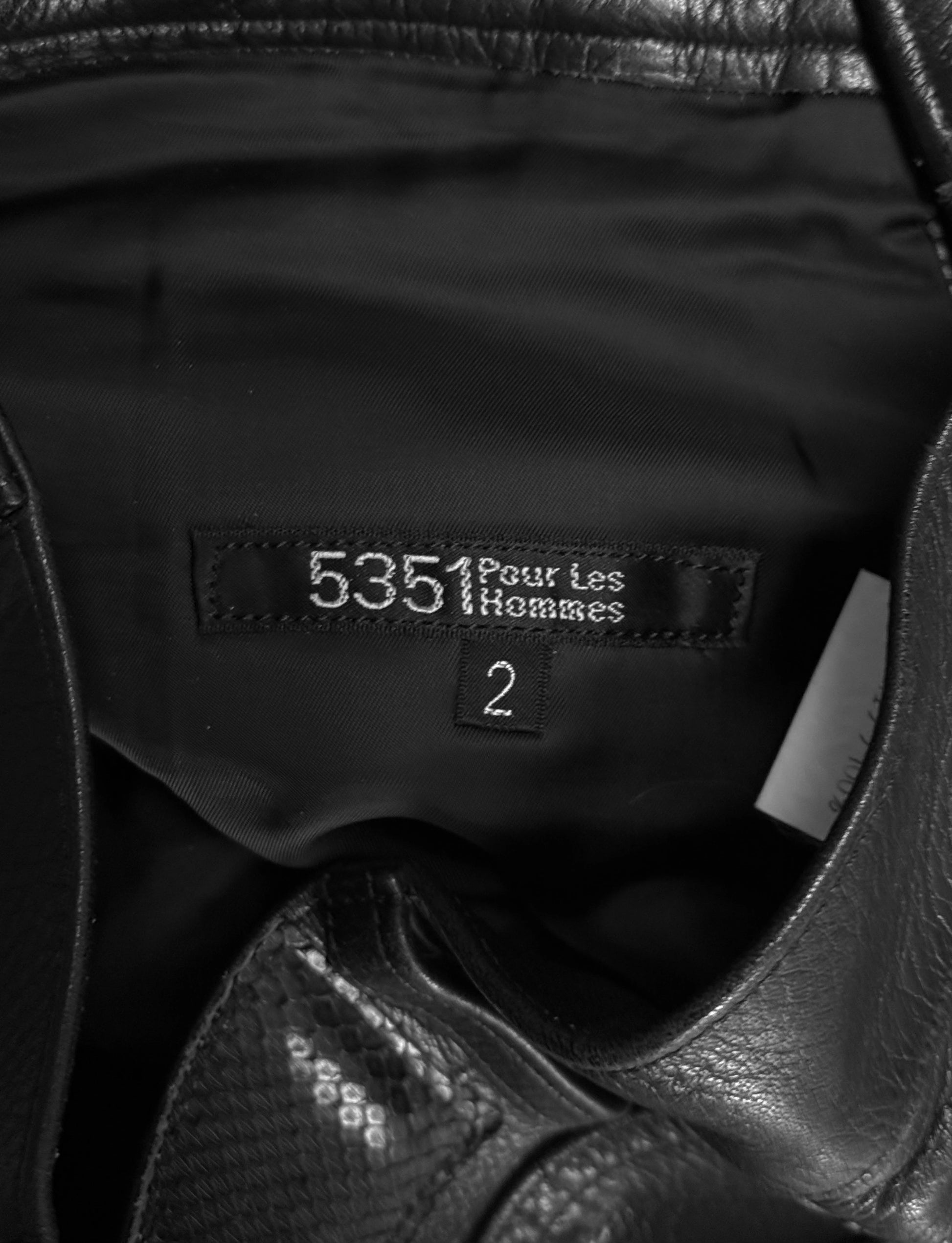 Close-up of a black leather jacket with a brand label on a dark background