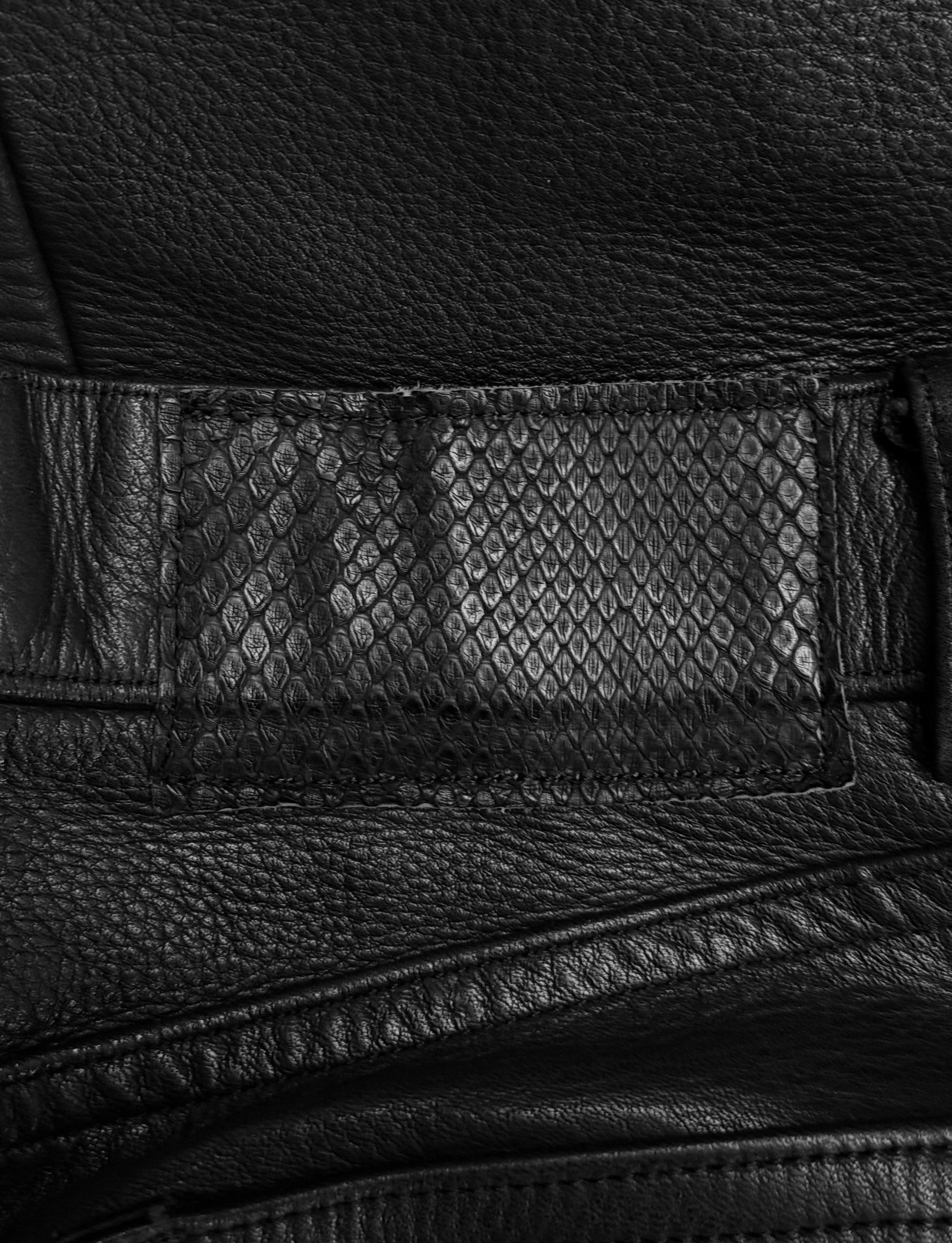 Close-up of black leather texture with a patterned patch.