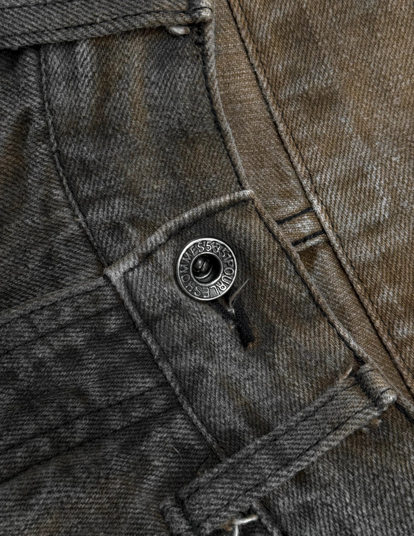 Close-up of a button on a pair of dark gray denim shorts.