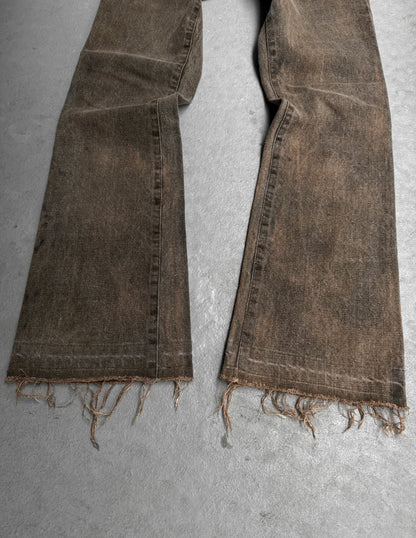 Brown distressed jeans laid flat on a gray surface
