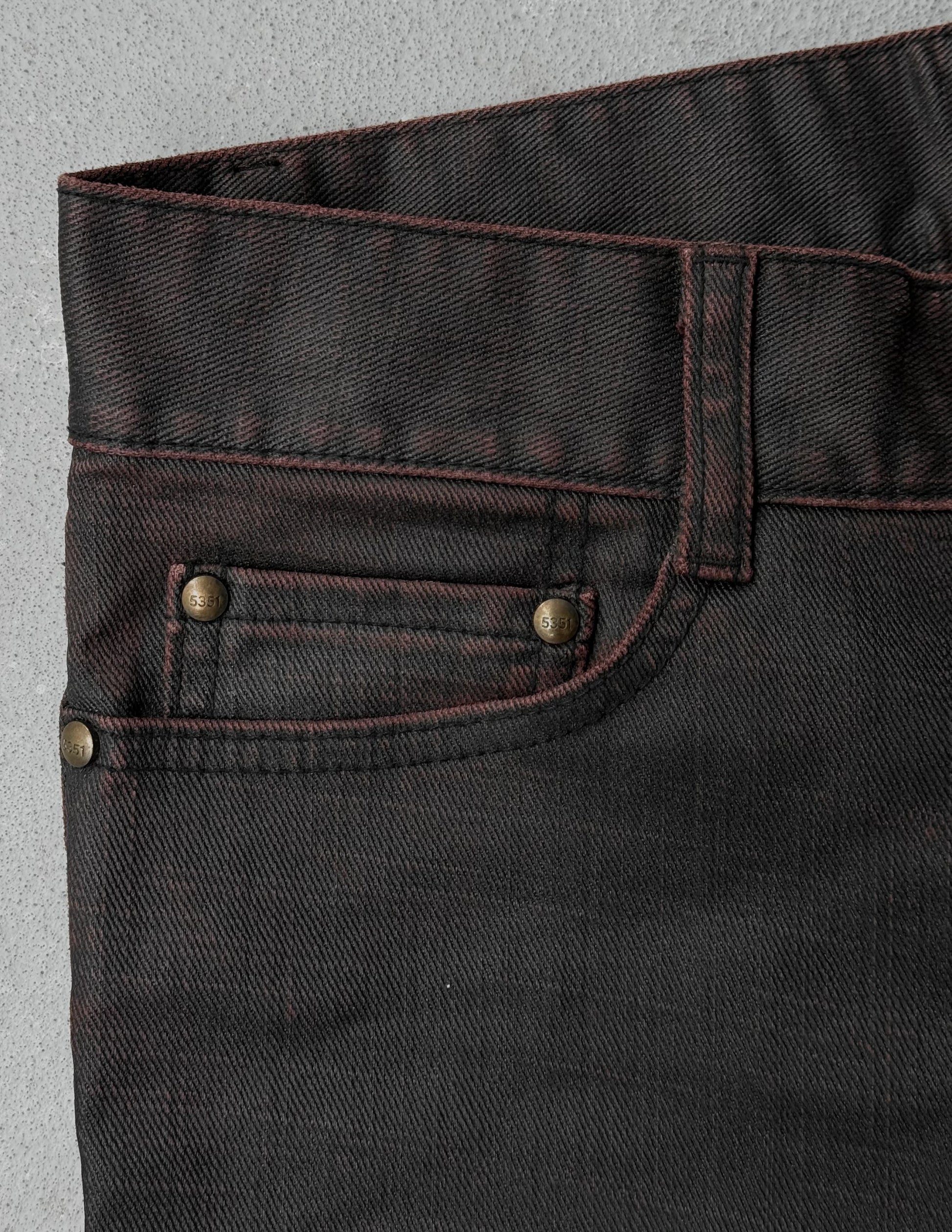 Close-up of dark brown denim fabric with button and stitching details on a gray background