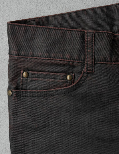 Close-up of dark brown denim fabric with button and stitching details on a gray background