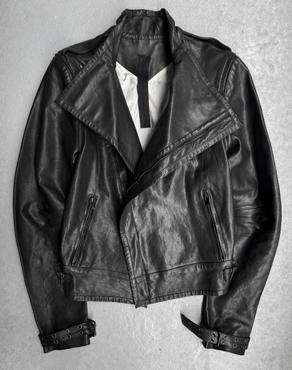 The Gareth Pugh AW09 Detachable Sleeves Horse Leather Riders Jacket, featuring zippered pockets, wide lapels, and sleeve buckles, is displayed flat on a light gray surface—exemplifying Gareth Pughs avant-garde style.