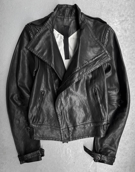 The Gareth Pugh AW09 Detachable Sleeves Horse Leather Riders Jacket, featuring zippered pockets, wide lapels, and sleeve buckles, is displayed flat on a light gray surface—exemplifying Gareth Pughs avant-garde style.