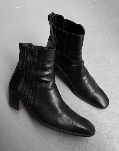 A pair of Saint Laurent Paris YSL Rive Gauche SS04 by Tom Ford ‘Johnny’ leather boots with 40mm stacked heels and side stitching, in black, displayed on a light gray floor.