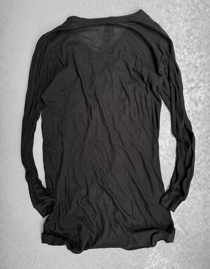 The Rick Owens SS10 “RELEASE” black sheer long-sleeve shirt lies flat and inside-out on a light gray textured surface, its wrinkled, semi-transparent fabric evoking the edgy, avant-garde style iconic to Rick Owens.