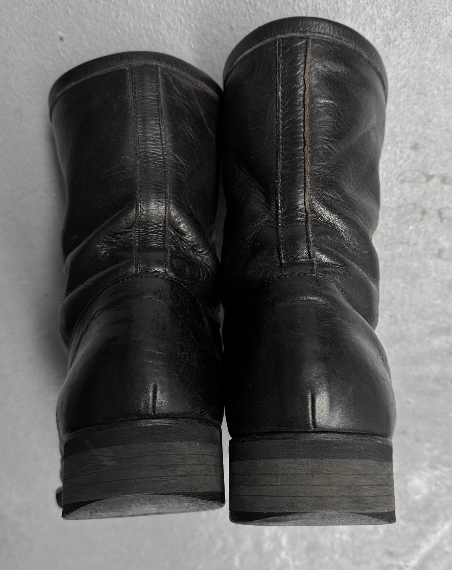 Pair of black leather boots on a textured gray surface