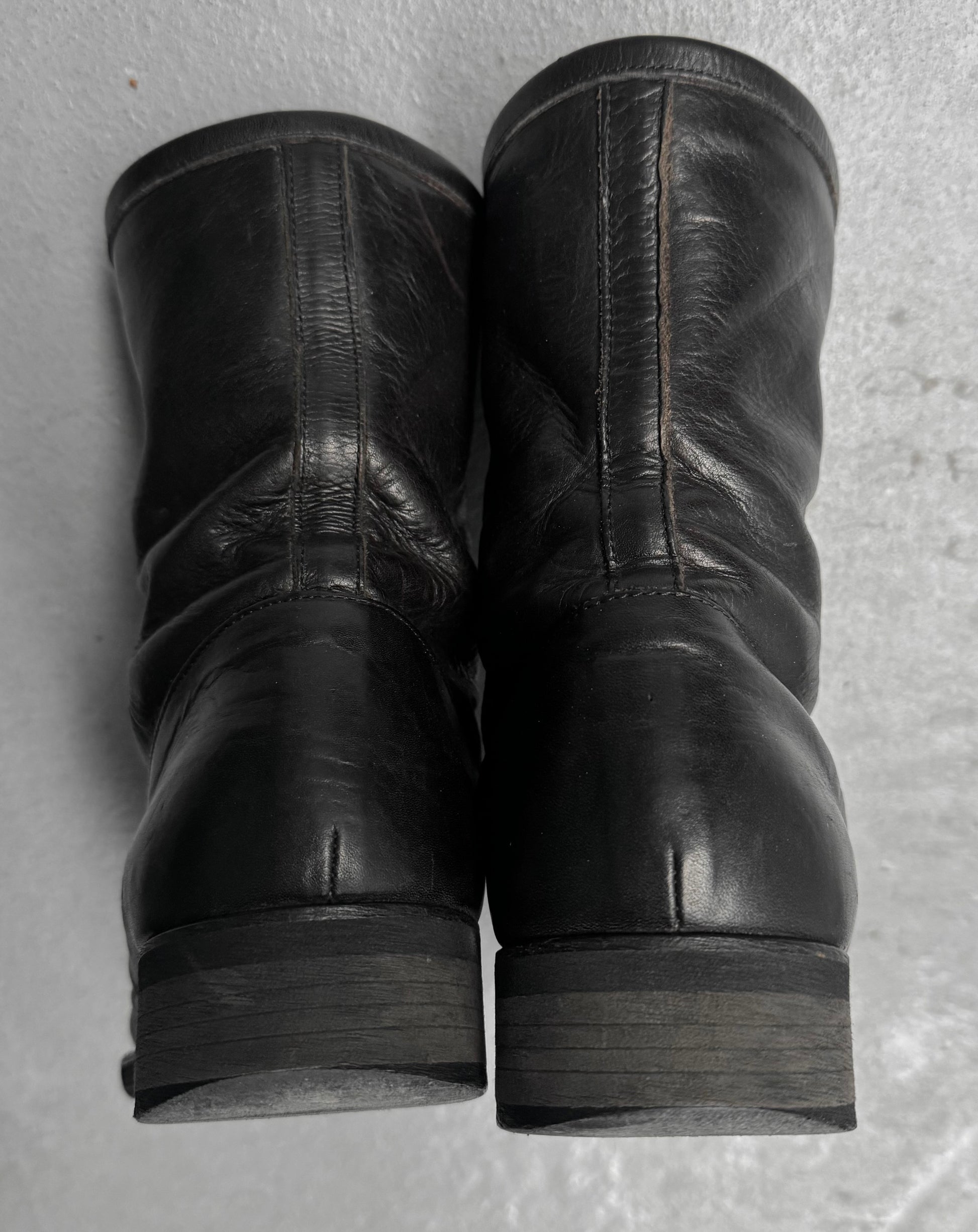 Pair of black leather boots on a textured gray surface