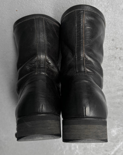 Pair of black leather boots on a textured gray surface