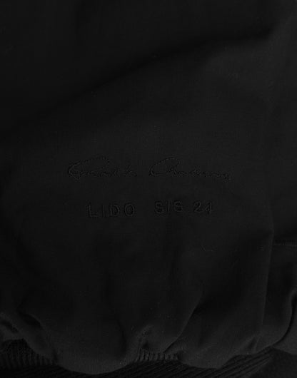 A close-up of black nubuck leather with subtle embossed LIDO SS24 text and a faint cursive signature, capturing the avant-garde style of the Rick Owens SS24 “LIDO” Cropped Flight Bomber Jacket.