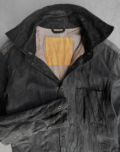 A black, washable wrinkle nubuck leather shirt by Kyoji Maruyama from the early 00s is laid flat with a high collar, front pocket, striped lining, tan inner patch, and the left sleeve folded across the body.