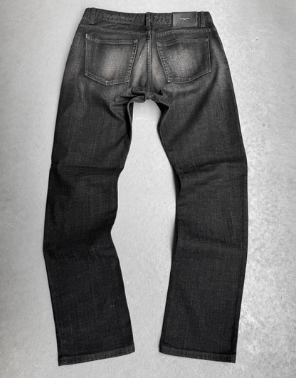 The Surface To Air SS14 Faded Black Bootcut Skinny Denim is displayed flat on a grey surface, showcasing the back with visible pockets and subtle seam fading—ideal for those who value urban style in modern menswear.