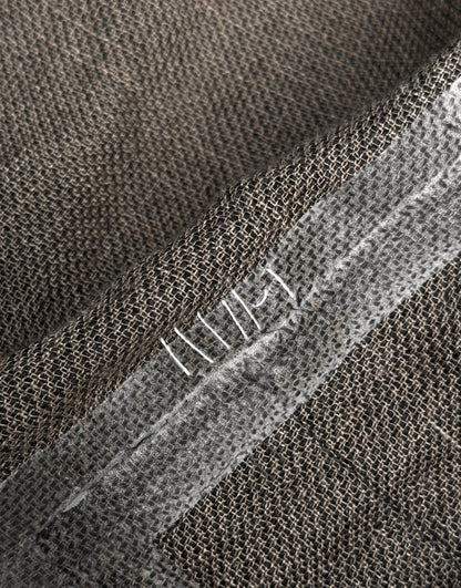 Close-up of brown burlap fabric from the TaichiMurakami “Coin” Taped Seam Collarless Work Blazer, featuring a reinforced seam with white hand stitching and translucent tape, reflecting the brand’s signature industrial minimalism.