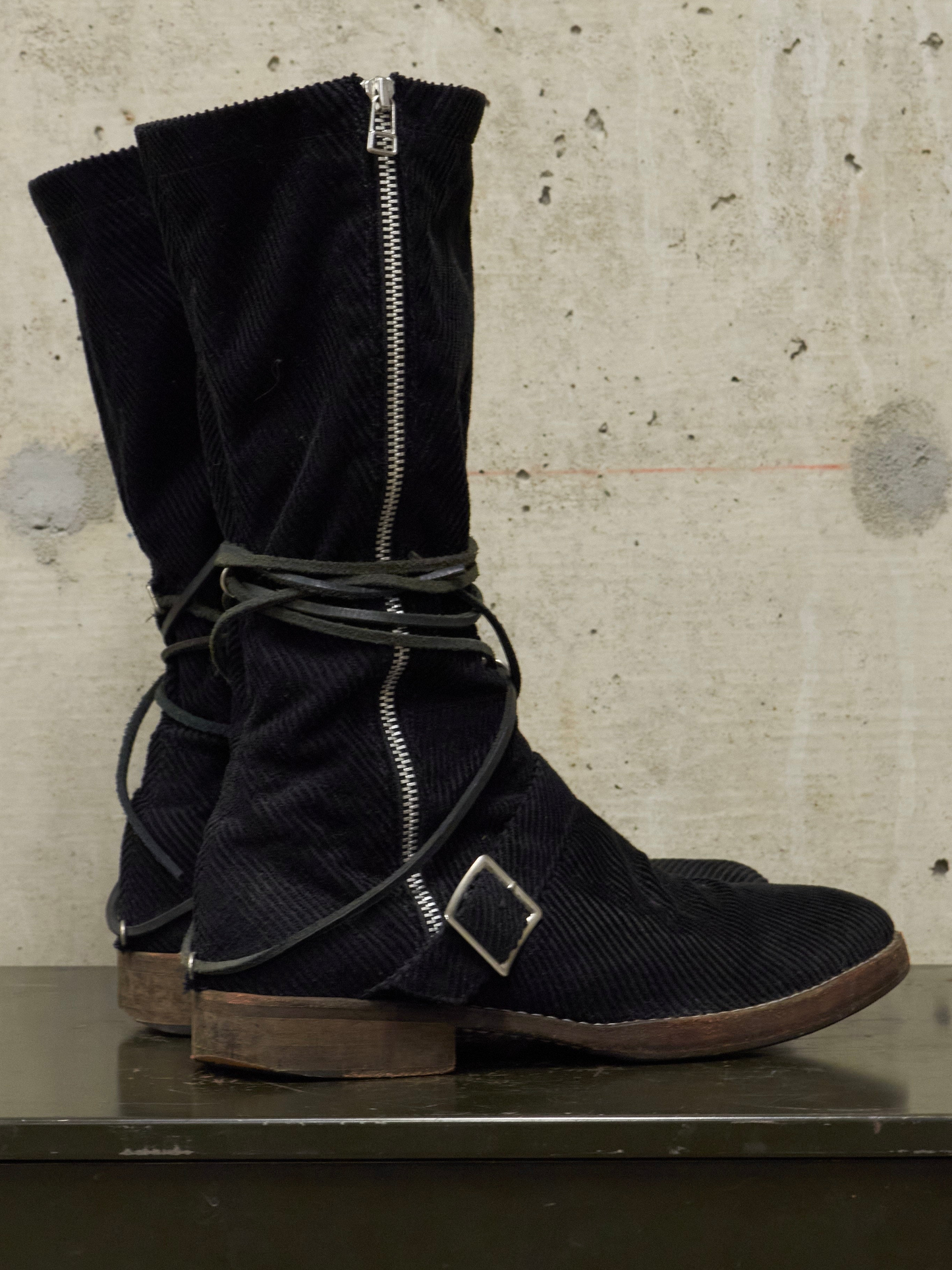 Black corduroy boots with zippers on a textured surface