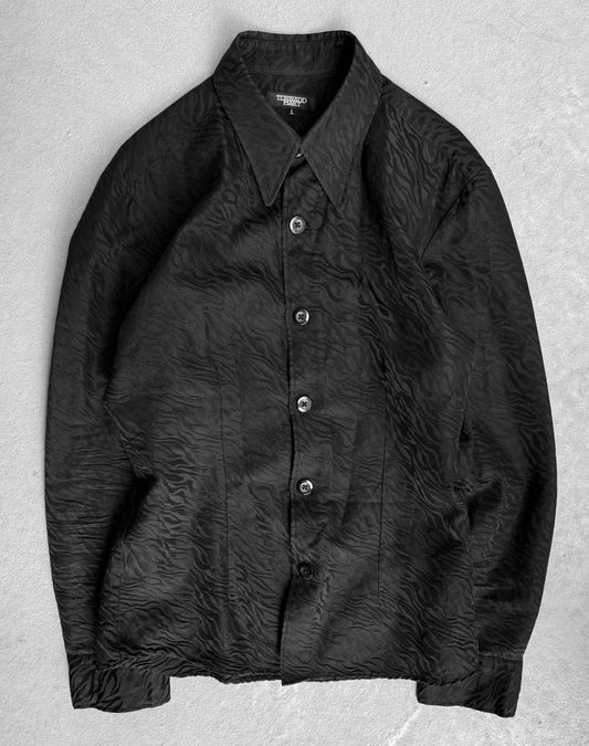 The Tornado Mart Early 00s Zebra Imprint Button-up Shirt is a black long-sleeve collared design with a wrinkled texture, laid flat on light gray. It features five visible buttons and embodies the luxurious fabric style reminiscent of Japanese mens fashion by Tornado Mart.