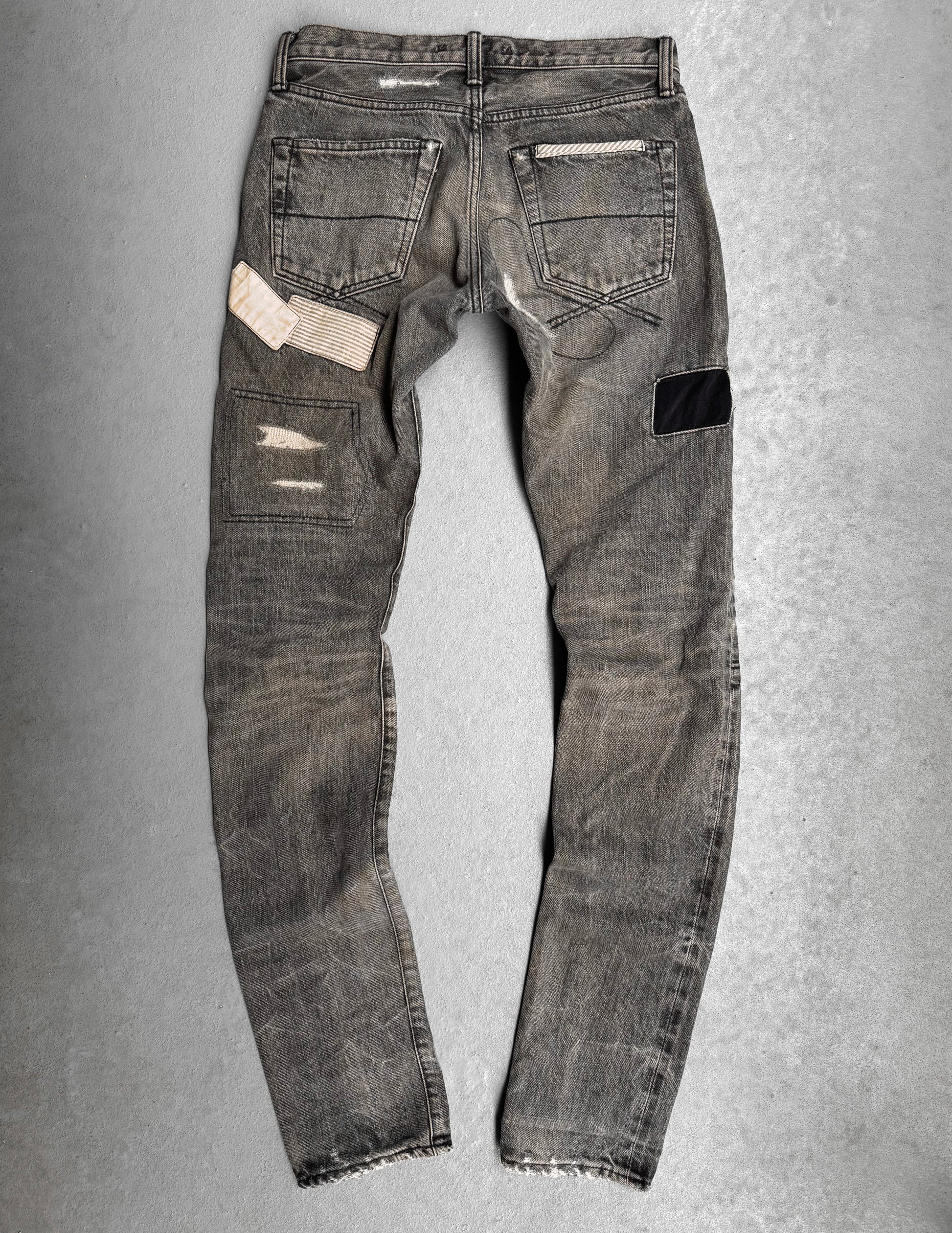 Mihara Yasuhiro AW10 Double-pockets Repair Patchwork Selvedge Denim—gray jeans featuring visible distressing, patch repairs (white striped, black), and frayed hems, ideal for a streetwear-inspired look.