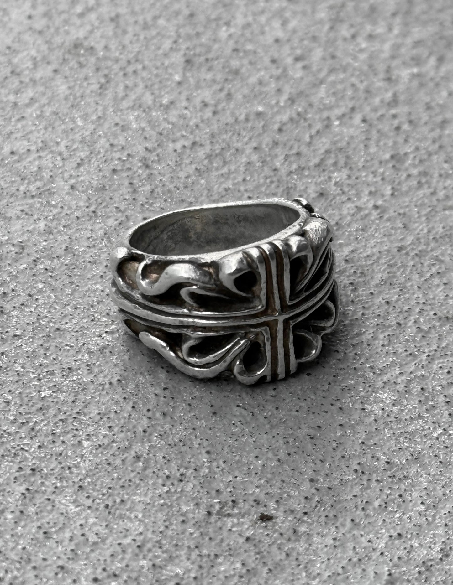 Silver ring with intricate design on a gray surface