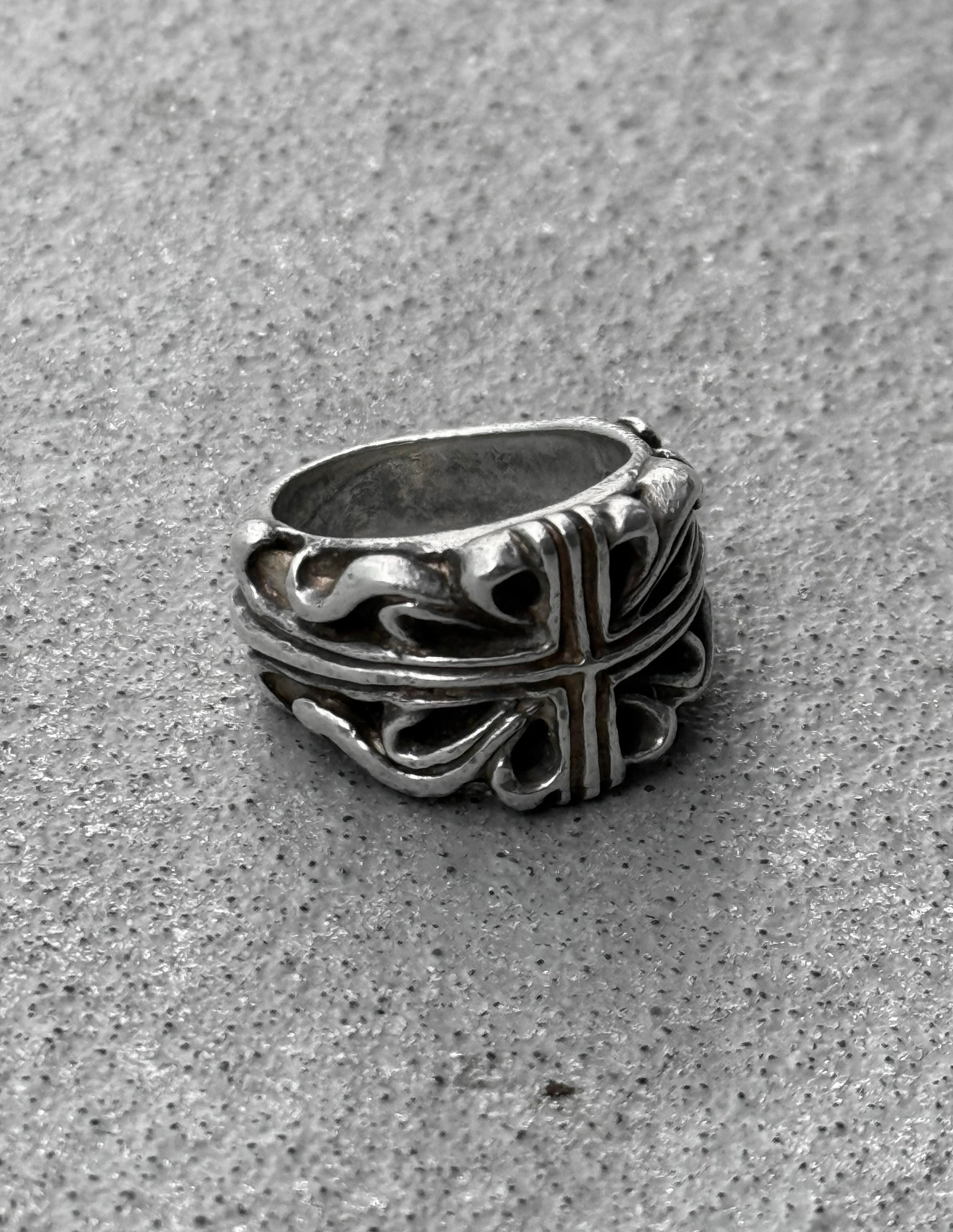 Silver ring with intricate design on a gray surface