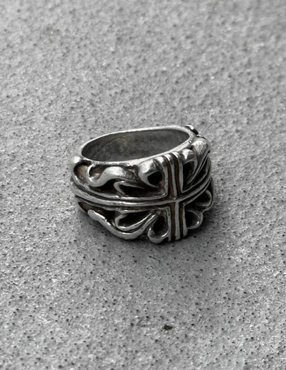 Silver ring with intricate design on a gray surface