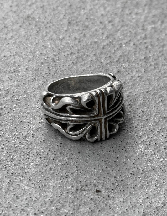 Silver ring with intricate design on a gray surface