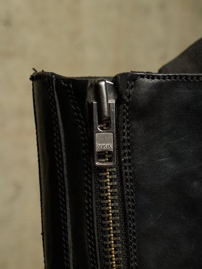 Close-up of a black leather zipper with a silver-toned metal pull tab engraved with the brand name YIK.