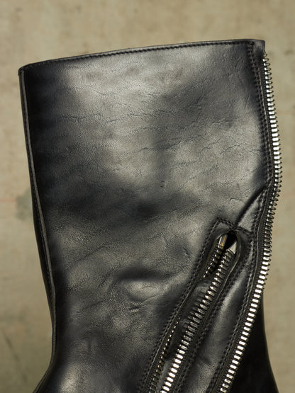 Close-up of a black leather boot featuring a prominent silver zipper running vertically along the side.