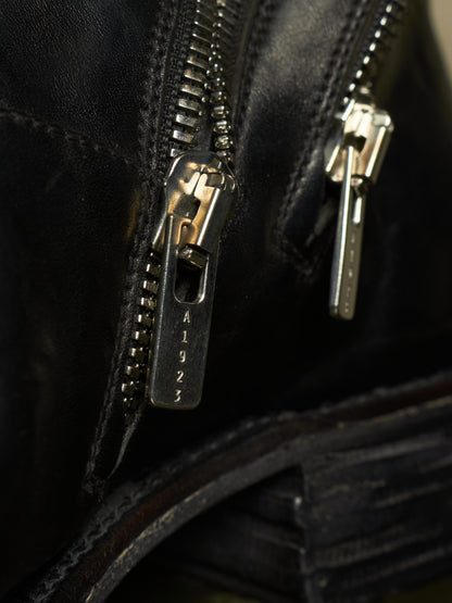 Close-up of a black leather zipper with a silver-toned metal pull tab engraved with the number 1923.